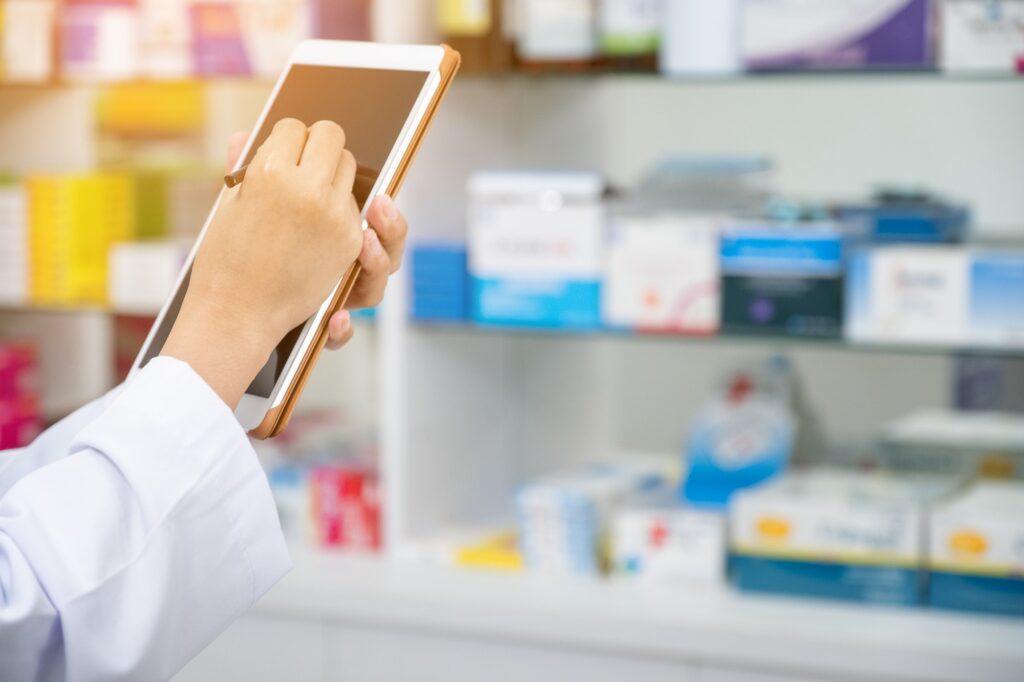 Pharmacist working with a tablet computer in the pharmacy holding it in her hand